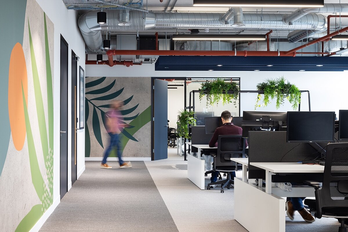 A modernised office space featuring newly installed ergonomic workstations, and collaborative spaces with stylish furniture and leaves painted on walls. The photo showcases a clean, professional environment designed for improved productivity and employee comfort.